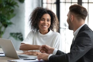A happy looking woman shakes the hand of a man in a suit