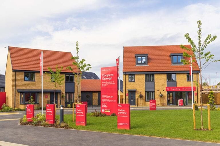 A new build housing development with lots of Taylor Wimpey signs and flags