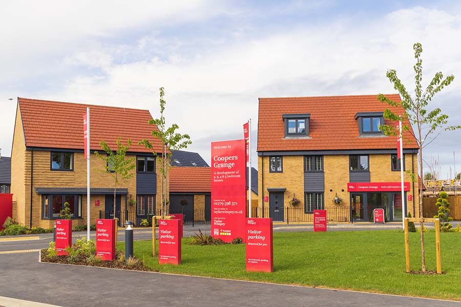 A new build housing development with lots of Taylor Wimpey signs and flags