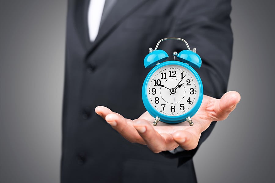 An outstretched hand holding an alarm clock