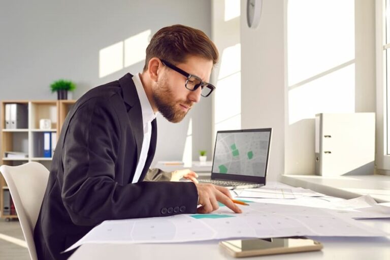 Professional surveyor in suit and glasses sitting at his table in office