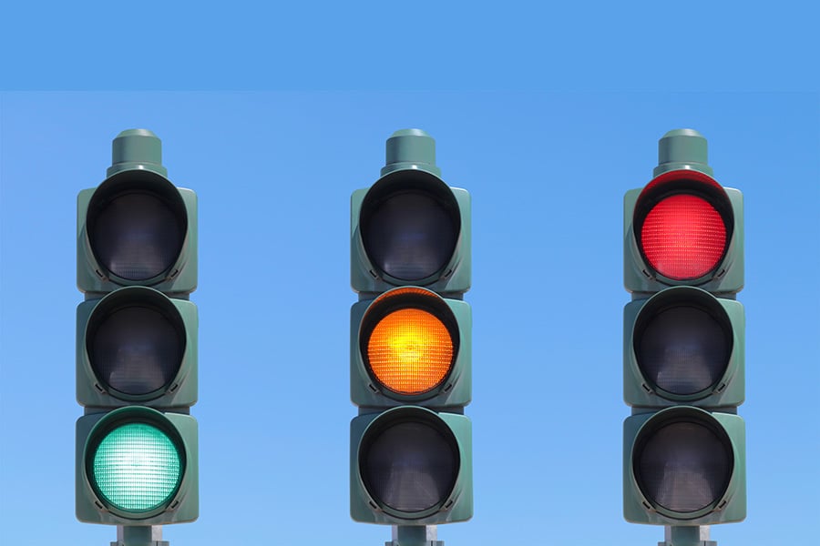 Three traffic lights, on each showing green, orange and red