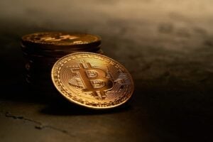Various golden cryptocurrencies highlighting Bitcoin coin with dark textured background