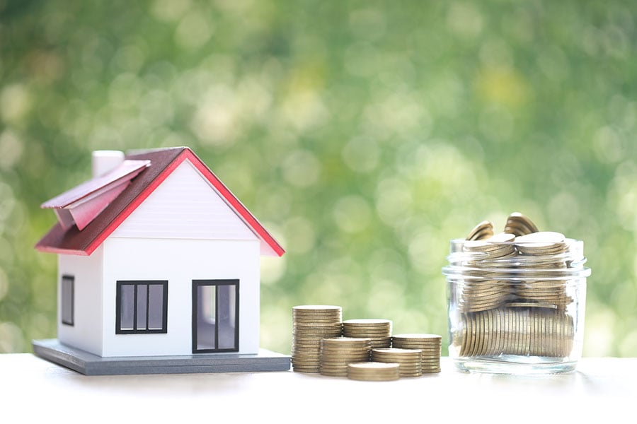 A small toy house next to a pile of coins