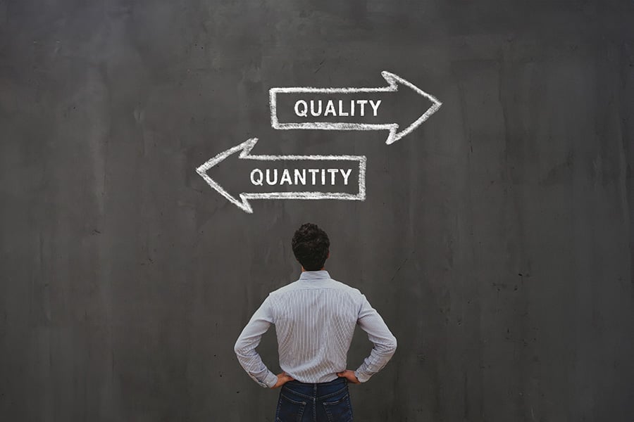 A man stares up at a chalkboard with the word quality and an arrow pointing one wa and quality with the arrow pointing the opposite way