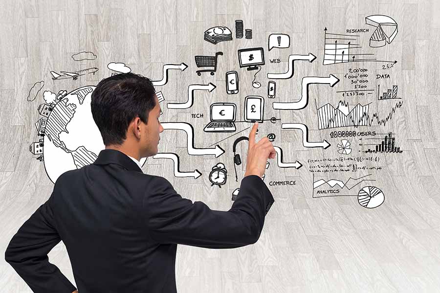 A composite image of a man in a black suit tracing money across a complex series of computers, phones and other financial equipment