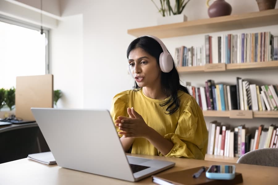 Digital interaction. Experienced young woman teacher tutor in wireless earphones