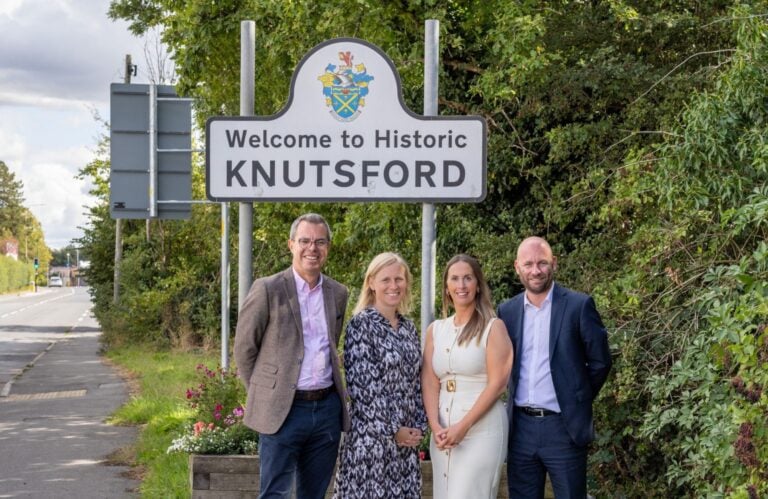 Solicitors stood outside a Knutsford road sign