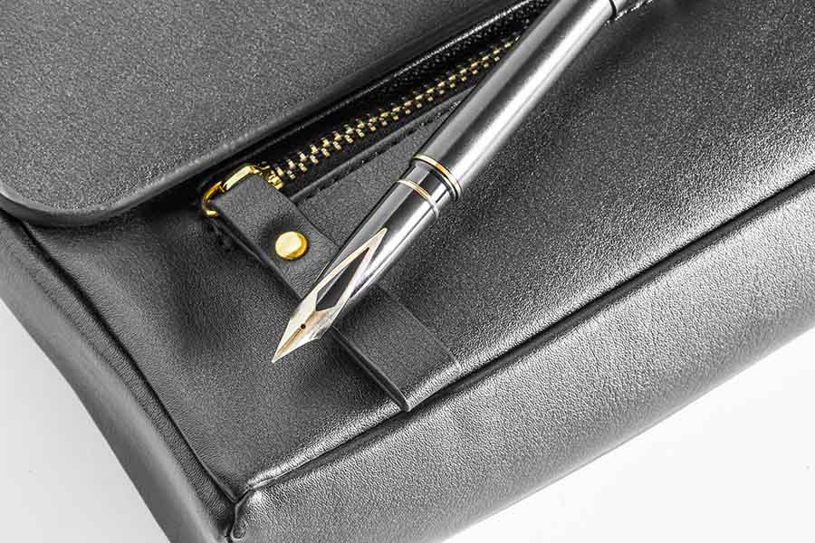 A black leather briefcase with a fountain pen laid on the top