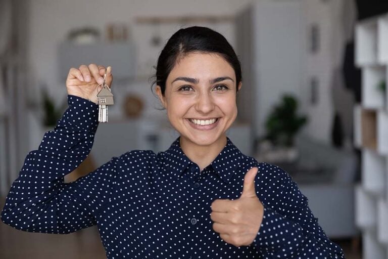 A smiling young woman holds up a set of house keys