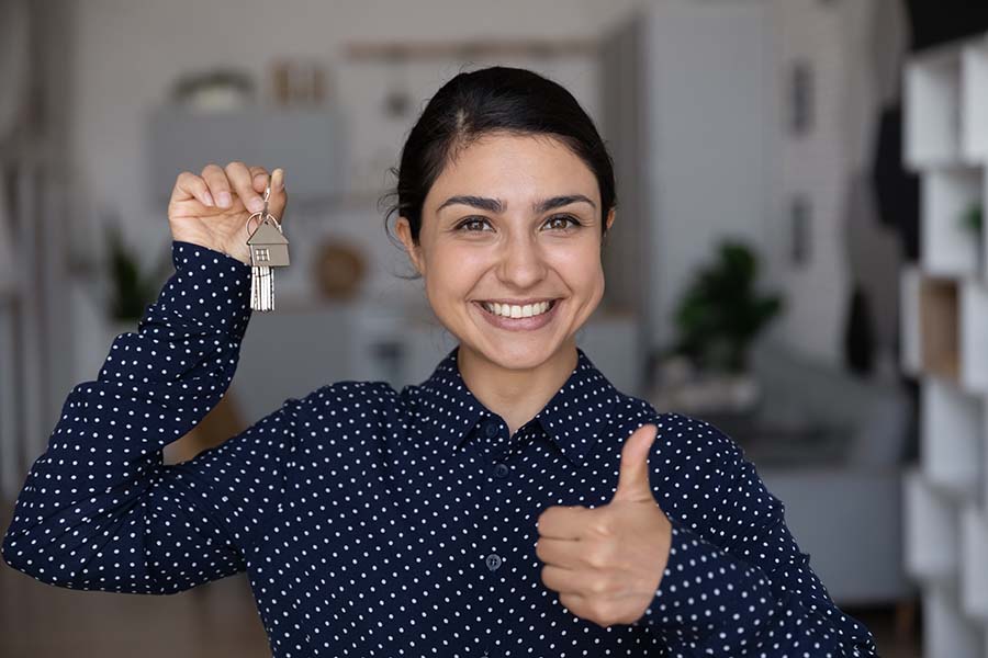 A smiling young woman holds up a set of house keys
