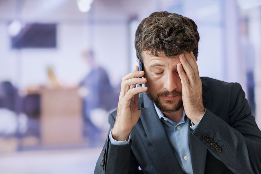 A frustrated looking man holding his phone to his ear