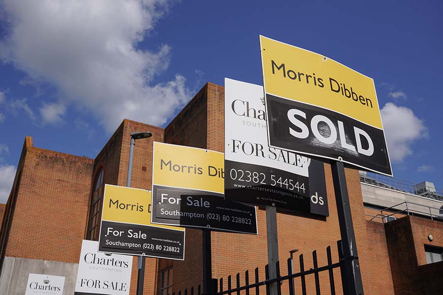 A row of five for sale signs outside a block of flats