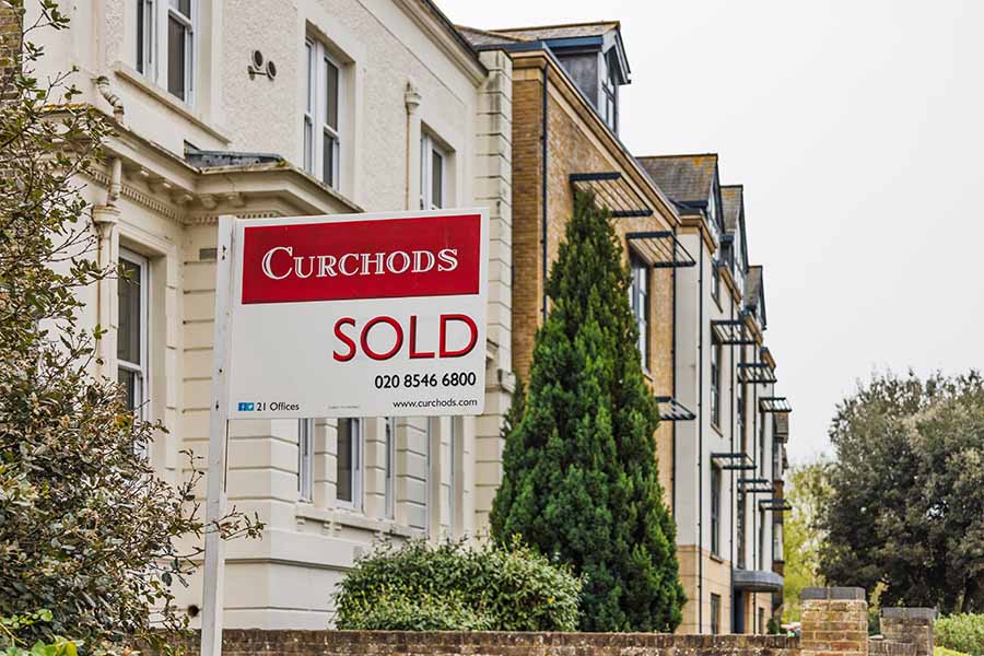 A sold sign in the foreground on a row of houses