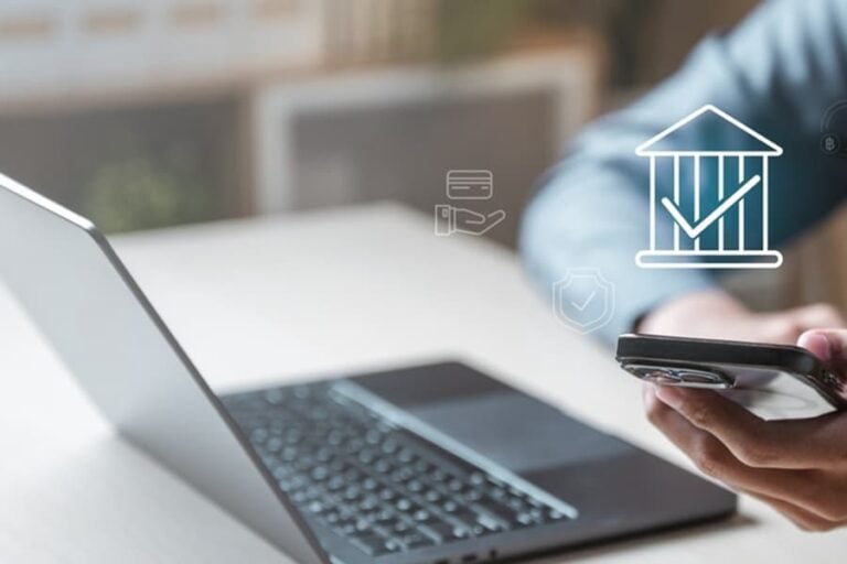 A person is using a laptop and a cell phone to look at a bank account..jpg