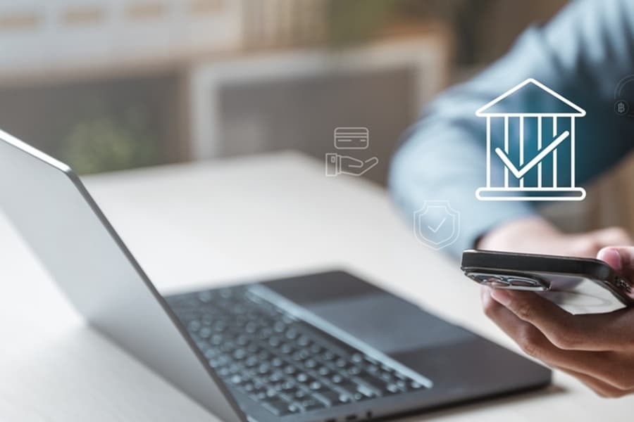 A person is using a laptop and a cell phone to look at a bank account..jpg