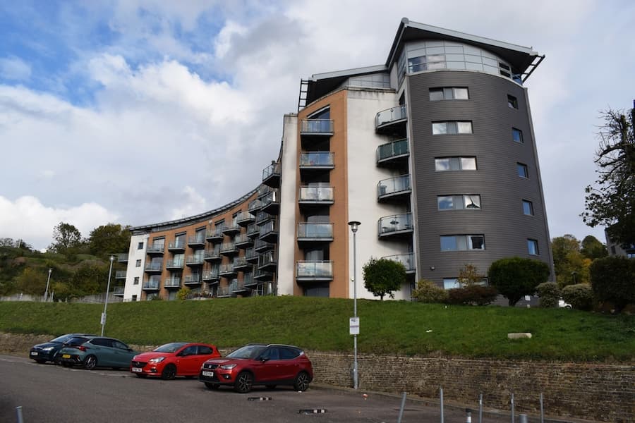 Upward View of a Multistory Modern Apartment Building on a Hill, Featuring Curved Facades