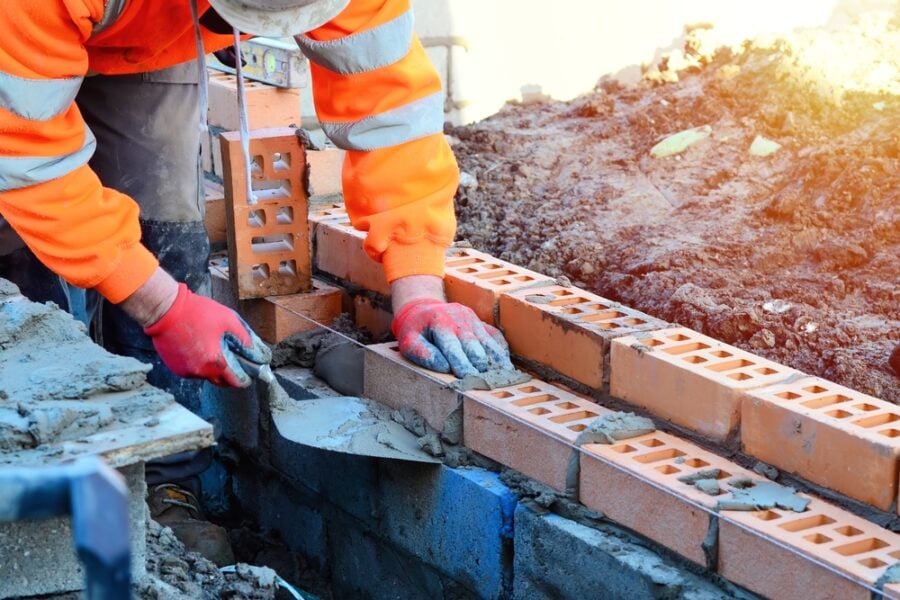 Brick layer laying bricks for a house